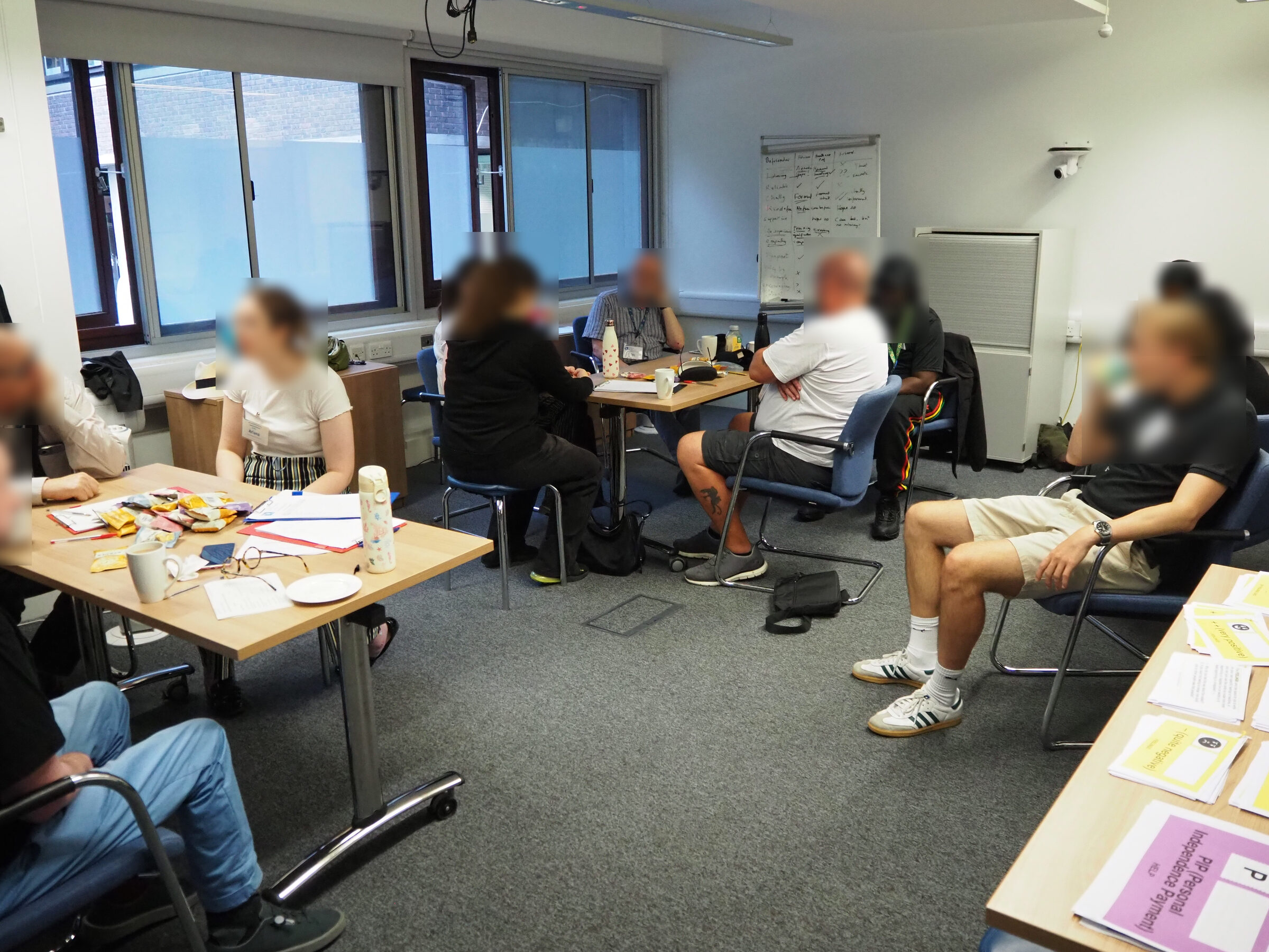 Wider view of a co-design workshop room with participants at multiple tables