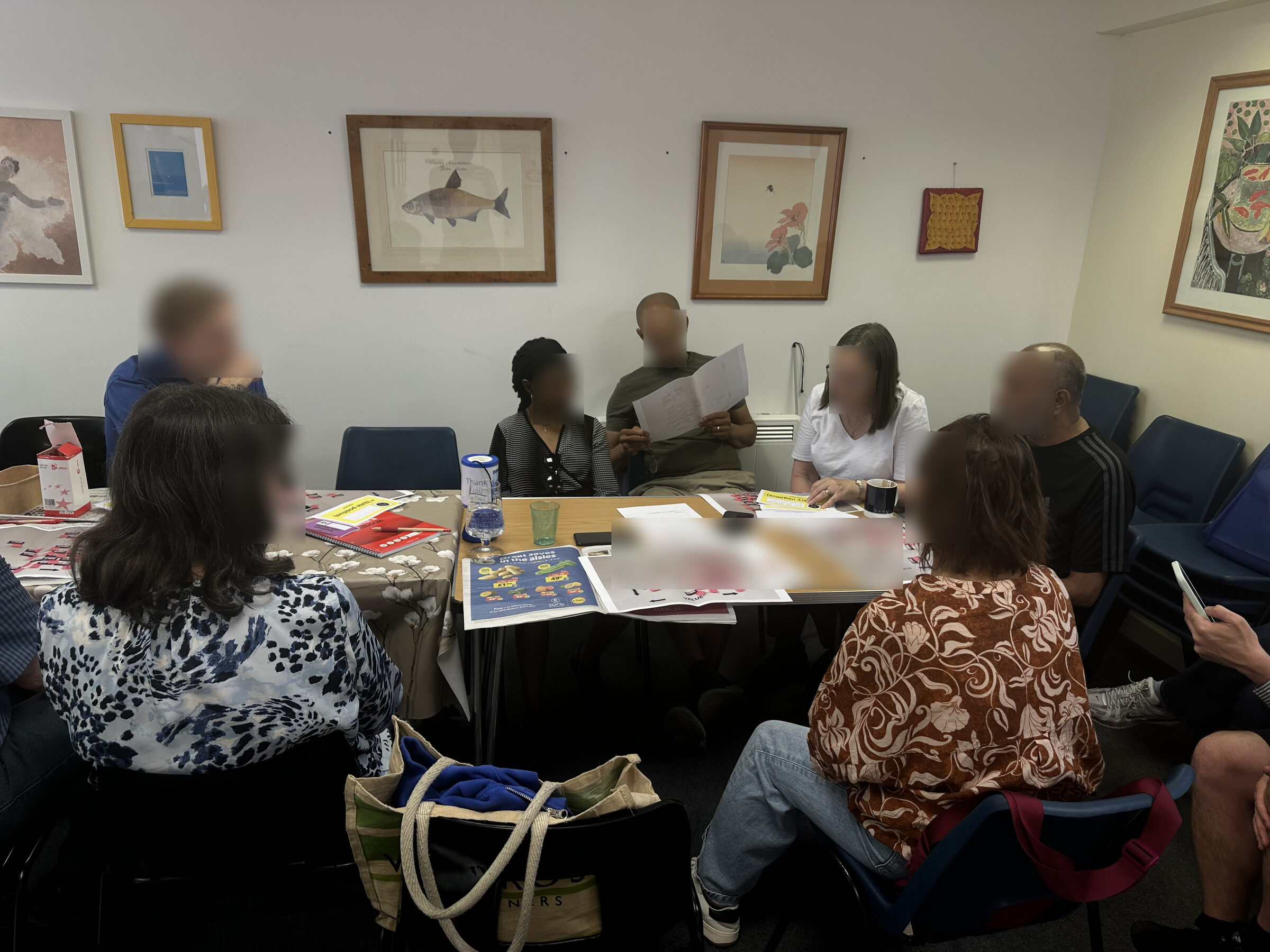 Co-design workshop session with stroke survivors with aphasia, seated around a table reviewing materials