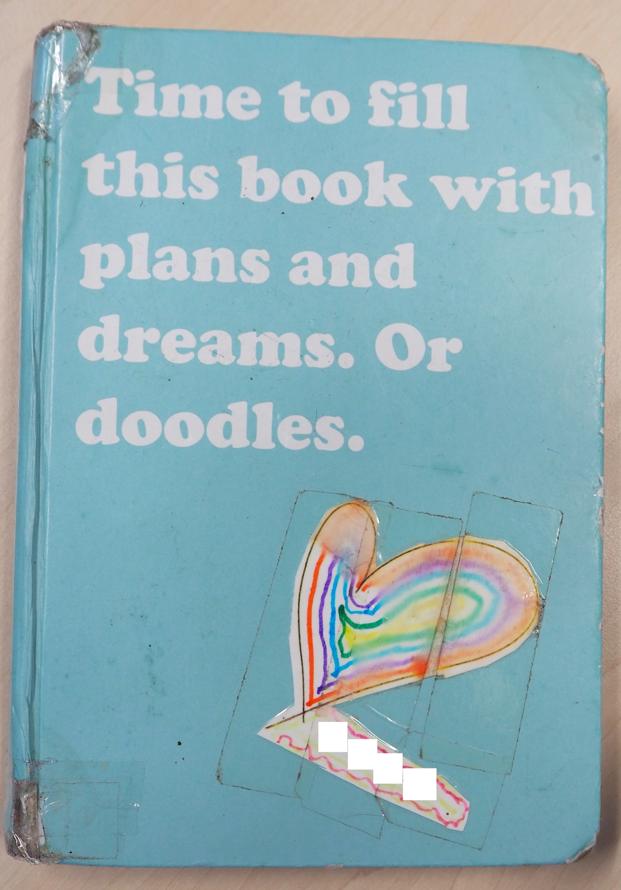 Zuzenna's aphasia diary — a teal notebook with a hand-drawn rainbow heart sticker