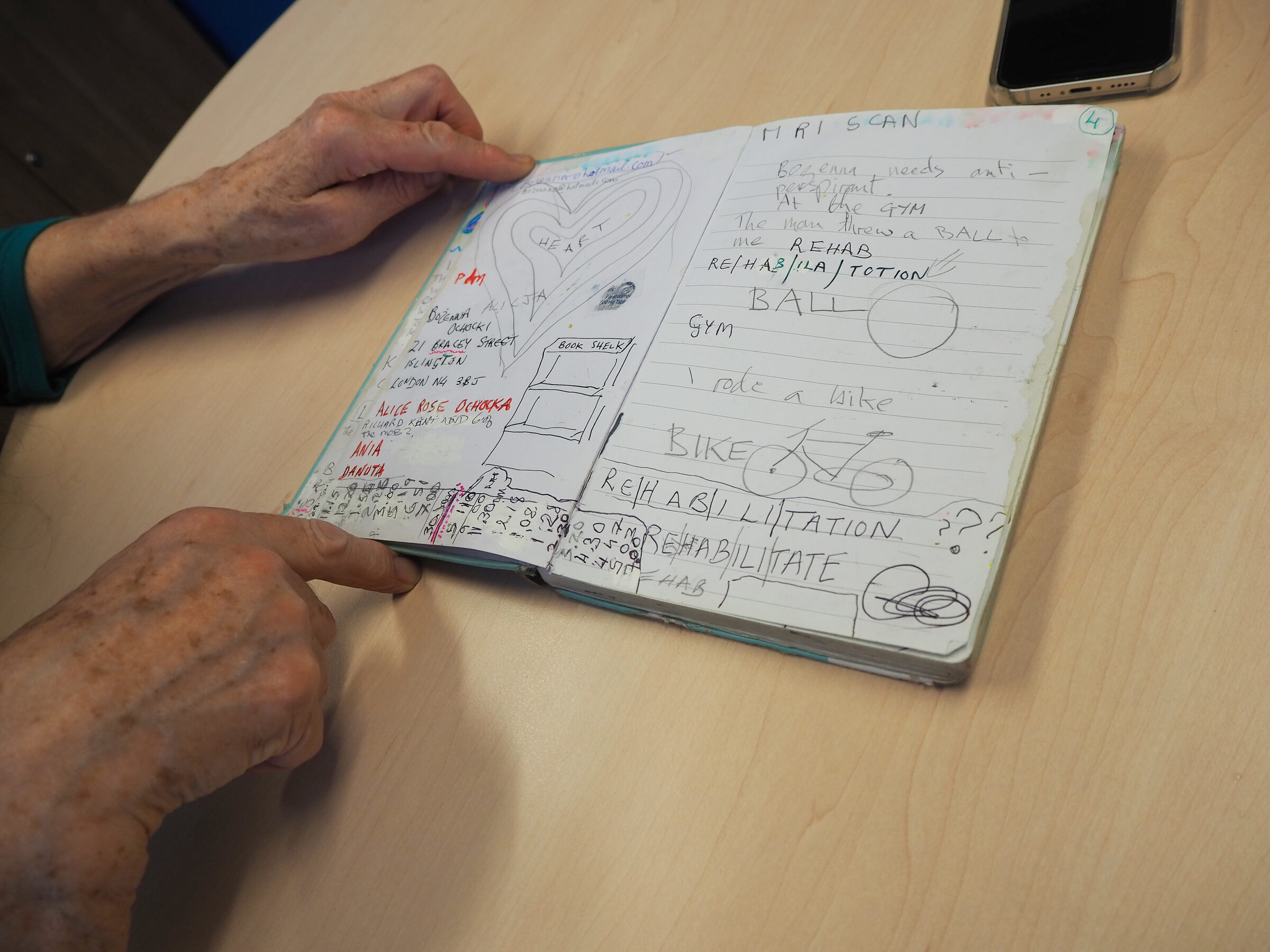 Zuzenna's hands holding open the diary, showing pages about MRI scans and rehabilitation exercises
